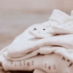 Białe ubranka niemowlęce z uroczymi zwierzątkami, przygotowanie wyprawki